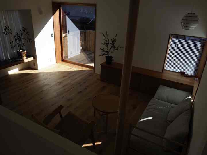 Warm wood tone living room connected to veranda with natural light, featuring simple and natural interior design
