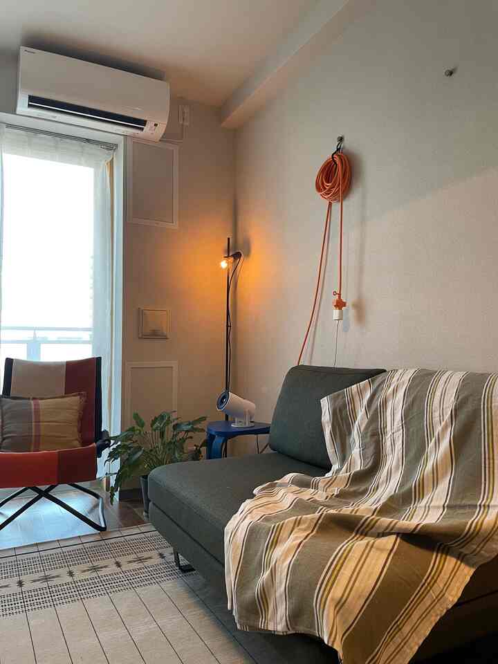 オレンジ色のコードと青いサイドテーブル、緑のソファが配置されたミッドセンチュリーモダン風のリビング