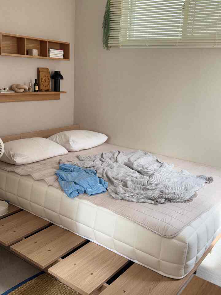 Natural-tone simple bedroom featuring a white mattress and wood-tone bed frame