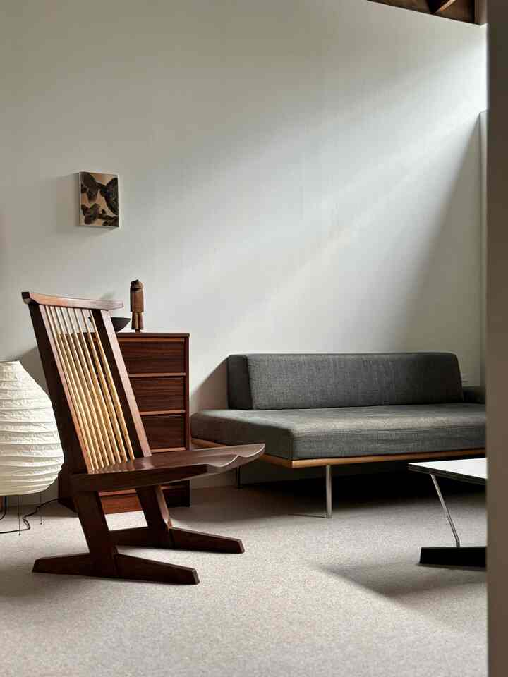 A natural modern living room featuring a gray sofa and brown wooden armchair with a clean, minimalist atmosphere