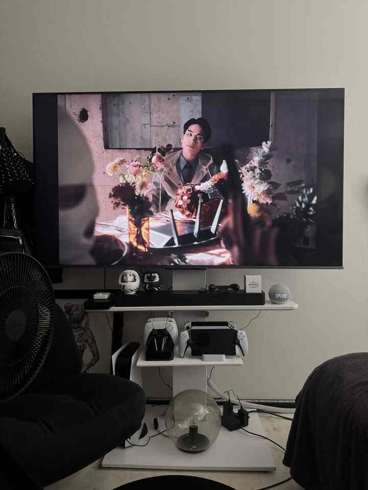 Black and white toned small game room featuring wall-mounted TV and gaming equipment on a modern TV stand