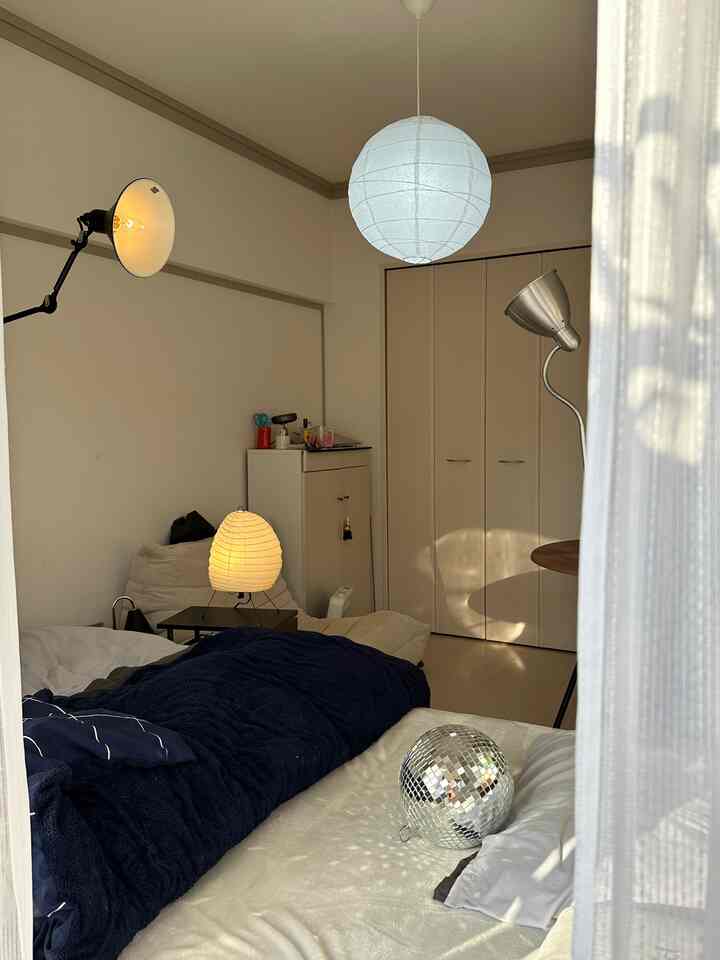 A mid-century modern bedroom in white and navy tones featuring pendant and floor lamps, soft curtains by the veranda creating cozy atmosphere
