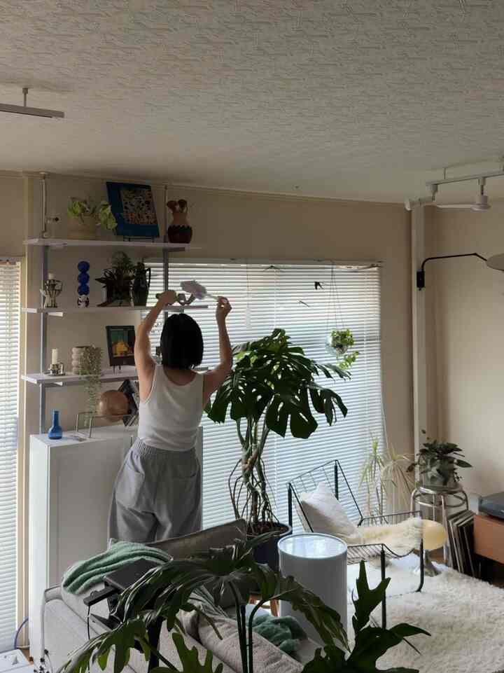 ナチュラルトーンのリビング、グレーのソファとアームチェア、豊かな観葉植物が配置された居心地の良い空間