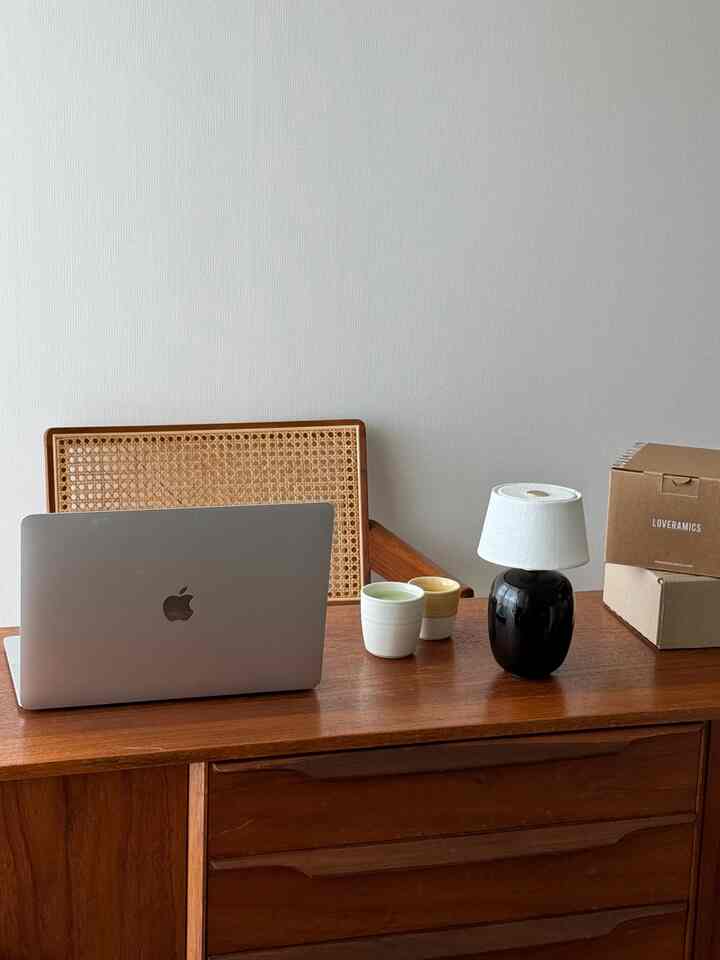 Brown cabinet and modern workspace featuring laptop and table lamp with a clean and minimalist atmosphere