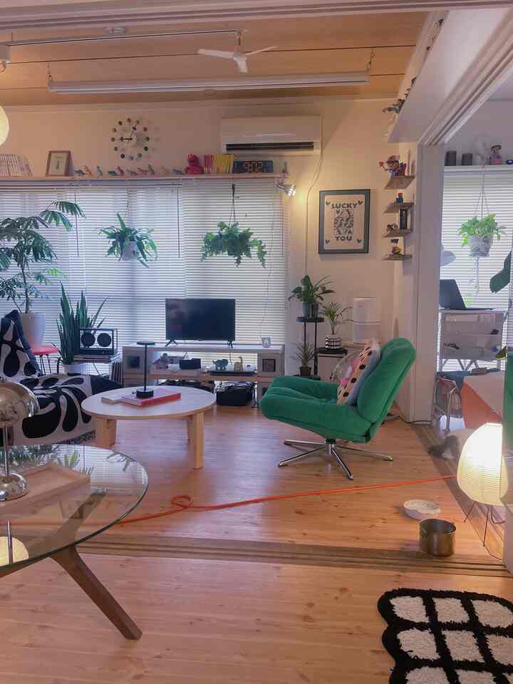 Wood toned living room with blinds on windows, featuring a round coffee table, sofas, and plants creating a cozy atmosphere