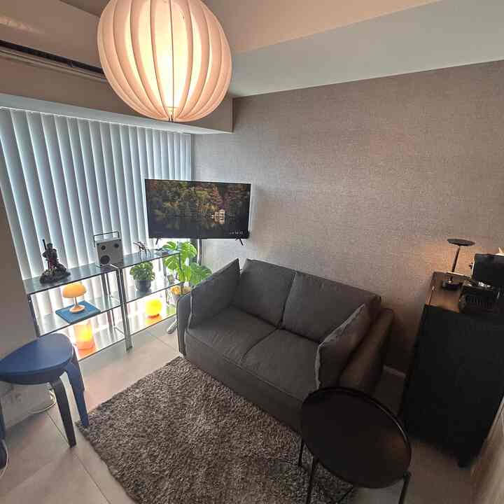 グレー調の6畳ワンルームリビング、大きなペンダントライトとソファ、ブラインドが配置されたモダンでミニマルな空間