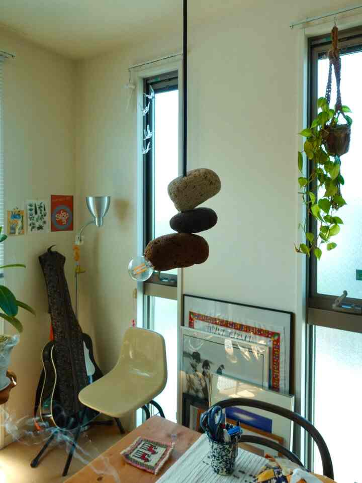 明るいウッドトーンとベージュ色調の1LDKリビング、植物とギターが配置されたミッドセンチュリーモダンなインテリア
