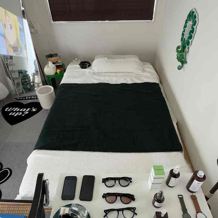 白とダークグリーンの色調の狭い寝室、シングルベッドとミニマルな小物が配置された落ち着いたインテリア