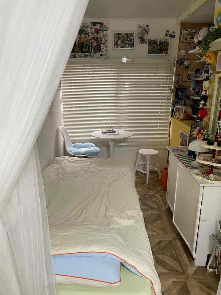 White and wood-tone compact 3-tatami bedroom featuring a small round dining table, framed pictures, and cushions creating a cozy atmosphere