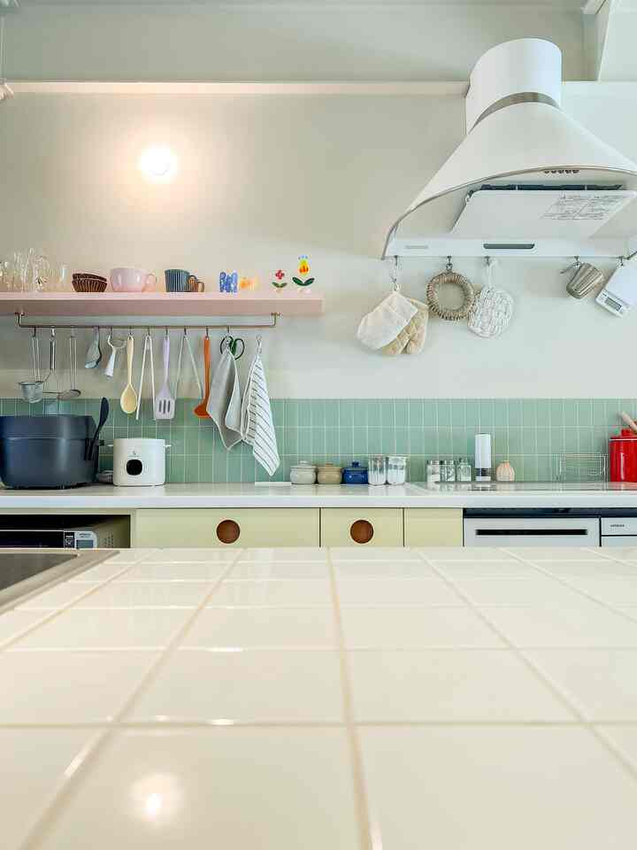 Pastel yellow and white kitchen featuring hanging kitchen utensils and neat storage ideas in a bright, cozy space