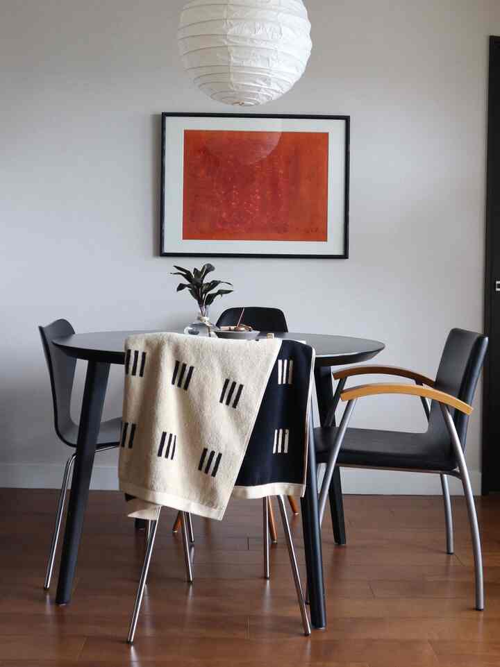 Dining room in black and brown tones featuring a black dining table and chairs, with an orange picture frame in a mid-century modern style