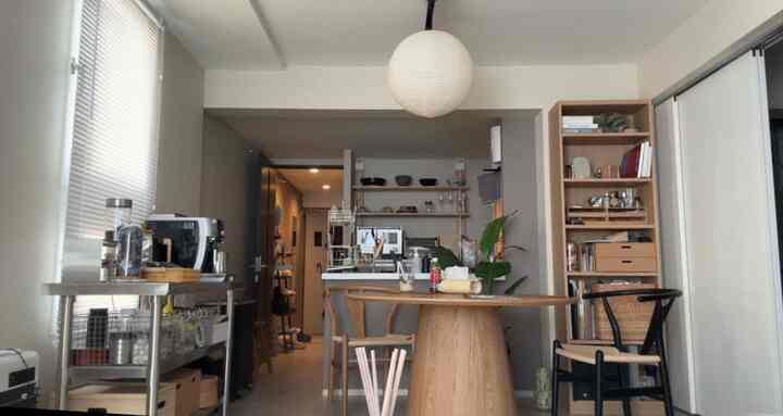White-walled Nordic style dining and kitchen space featuring natural wood furniture for two people