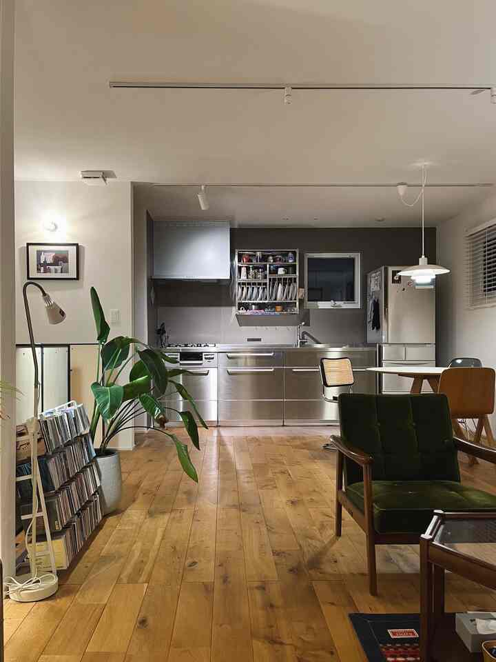 シルバーのステンレスキッチンと木目調の床が特徴の、モダンな家具が配置された雰囲気のあるキッチン・ダイニング空間