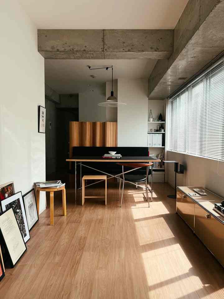 Modern natural living room with white walls, wood tone flooring, dining table, and stools arranged