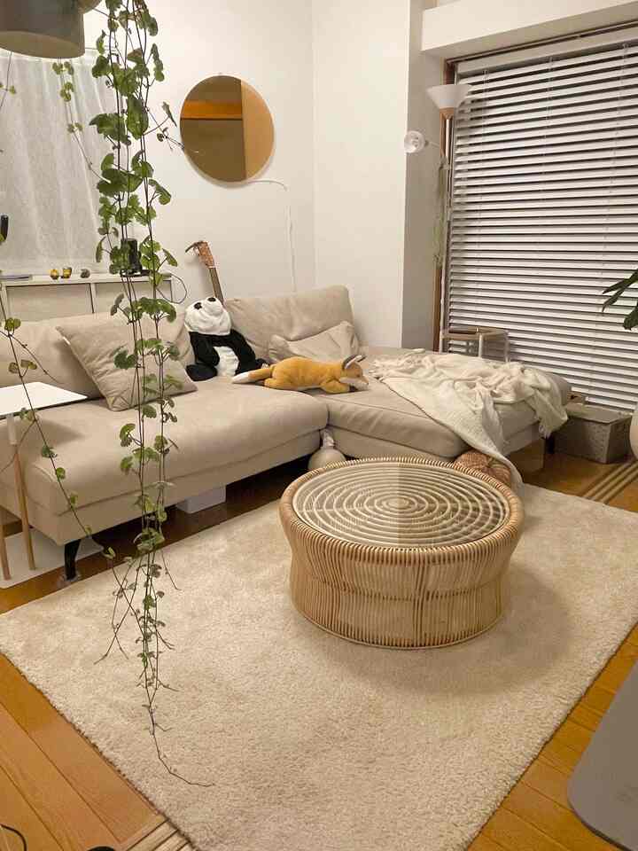 ナチュラルな色調の北欧リビング、ベージュのソファとラタン製の丸いコーヒーテーブル、クリーム色のラグが配置された雰囲気のあるインテリア