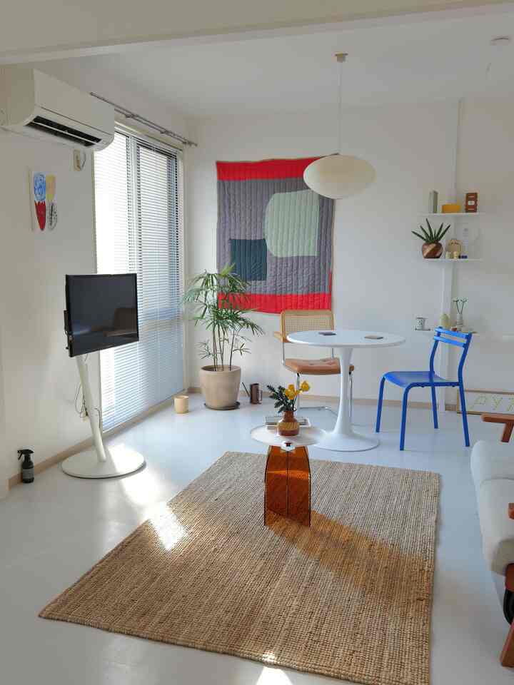 白と木目調が調和した北欧スタイルのリビングとダイニング、快適なラグとペンダントライト、自然な植物が配置された空間