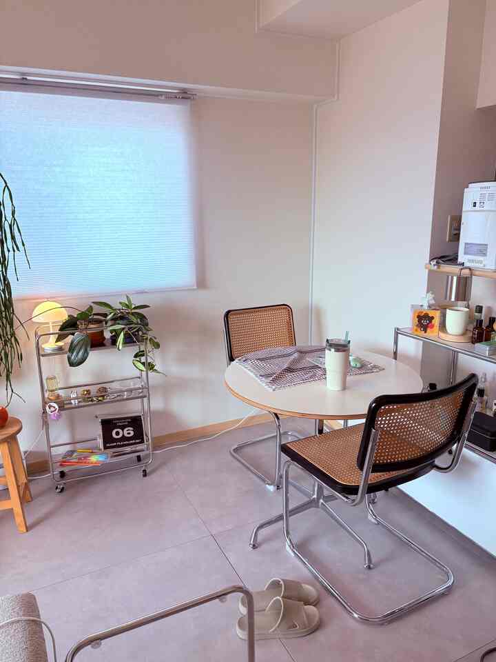 Soft white and gray toned round living room featuring rattan chairs and a round dining table in a Mid-Century Modern style