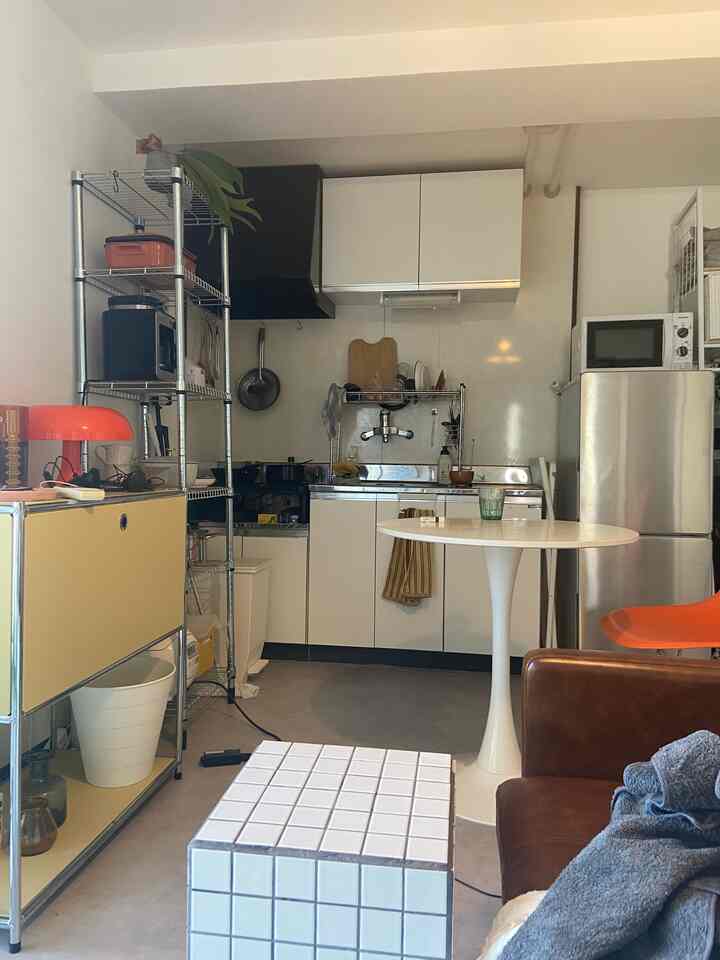 White and brown toned 1DK Mid-Century Modern living room and kitchen with small dining table and sofa arranged in cozy space