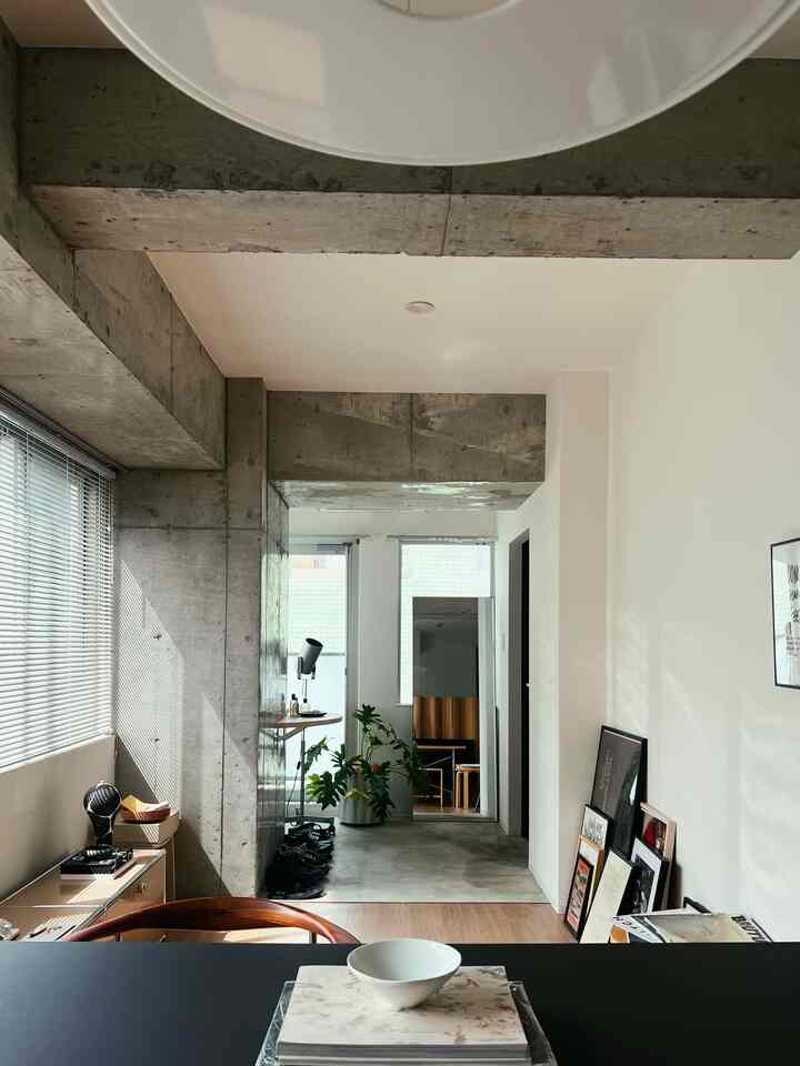 Minimal living and dining space with gray concrete, white walls, and wood tone furniture blending harmoniously