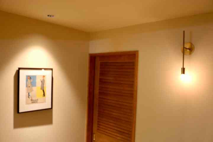 暖色調の茶色い木製のドアと左壁の額縁が配置された玄関のインテリア