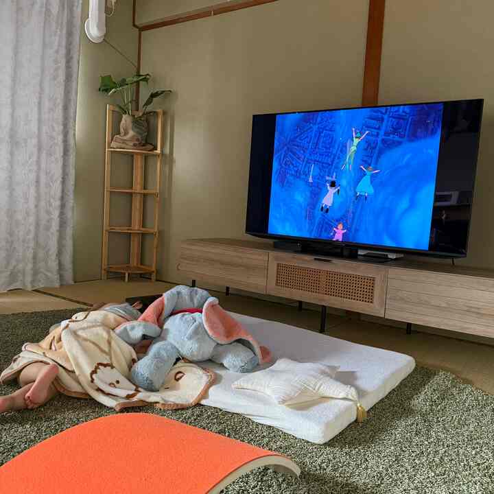 ナチュラルトーンの畳の部屋、子供の遊び場としてグリーンのラグと木製家具が配置された温かみのあるリビング