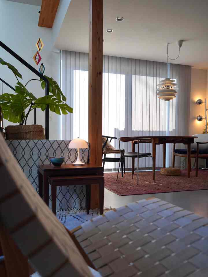 木目調とグレーが調和する北欧風ダイニングルーム、ペンダントライトとダイニングテーブル、チェアが配置された落ち着いた空間