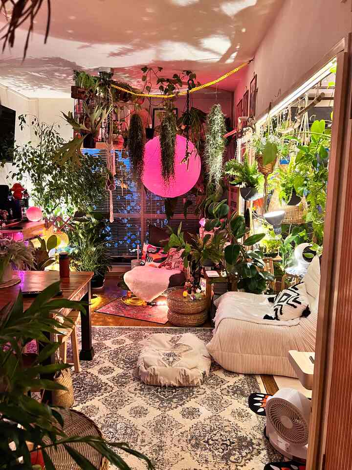 ピンク色の照明が映える植物あふれる居心地の良いリビングとダイニングの多目的スペース