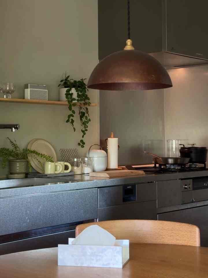 ナチュラルな木目調とステンレス素材が調和するモダンなキッチン、中央のペンダントライトが印象的なインテリア