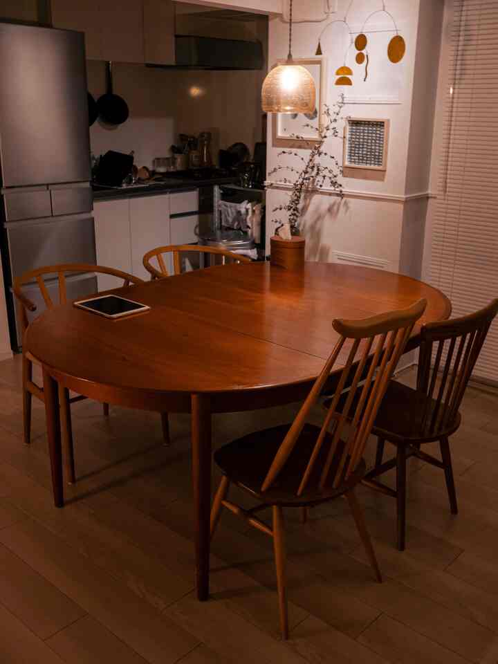 温かみのある木目調のダイニング、中央にヴィンテージ風のラウンドテーブルとチェアが配置された雰囲気のある空間