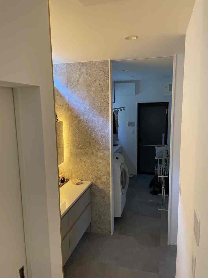 Bright white and gray toned long narrow bathroom featuring wash basin and washing machine with clean modern interior
