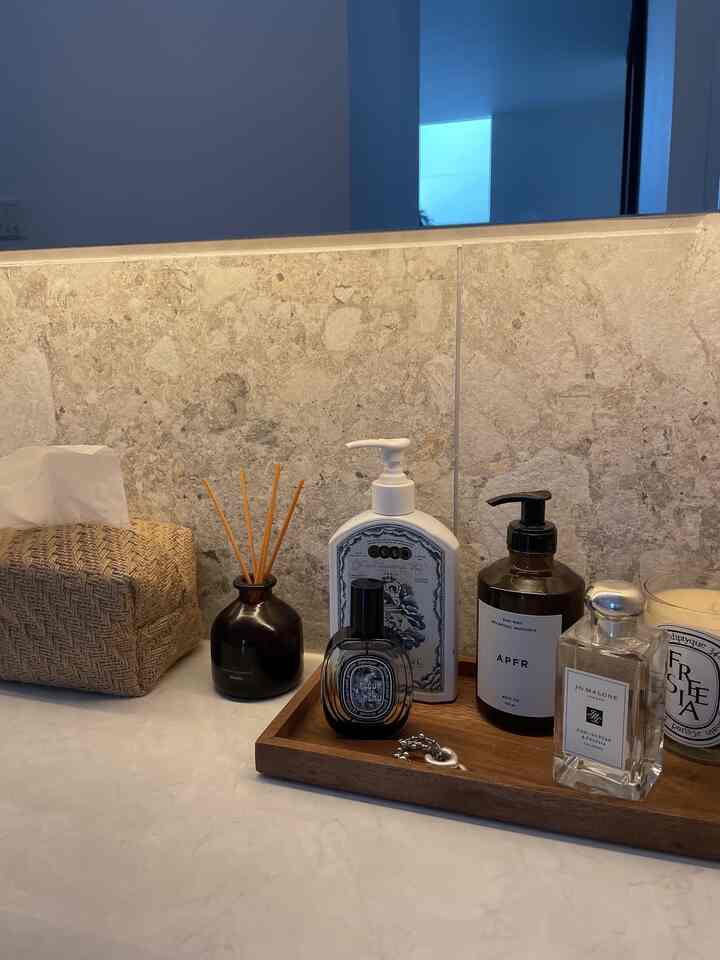 白とベージュの木目調が調和した洗面台、ディフューザーとキャンドルが配置されたシンプルで自然な雰囲気のインテリア