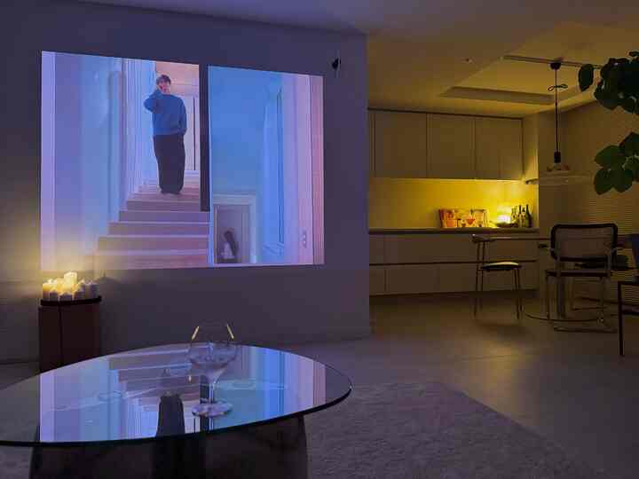 白とナチュラルカラーのリビング兼ダイニング、プロジェクターとキャンドルが配置された雰囲気のある空間