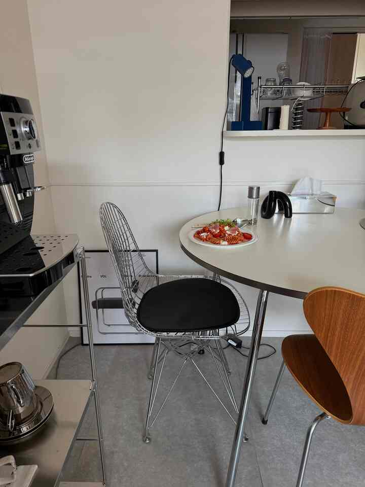 白とシルバーの色調のダイニング、モダンなダイニングテーブルとステンレス製チェアが配置されたシンプルなインテリア