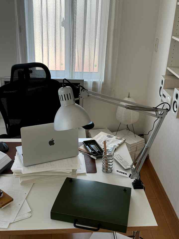Bright white-walled study room featuring a white desk with a black office chair and adjustable desk lamp, creating a clean home office ambiance