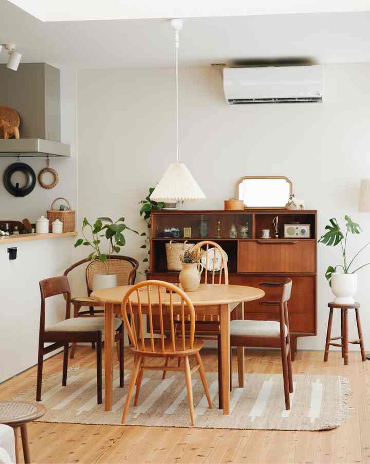 Natural-toned dining room featuring wooden dining table and chairs, jute rug, plants, and wooden cabinet creating a warm atmosphere