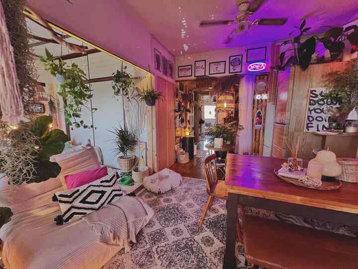 Natural-tone, plant-filled small cozy dining room and kitchen space with warm wooden furniture and colorful cushions