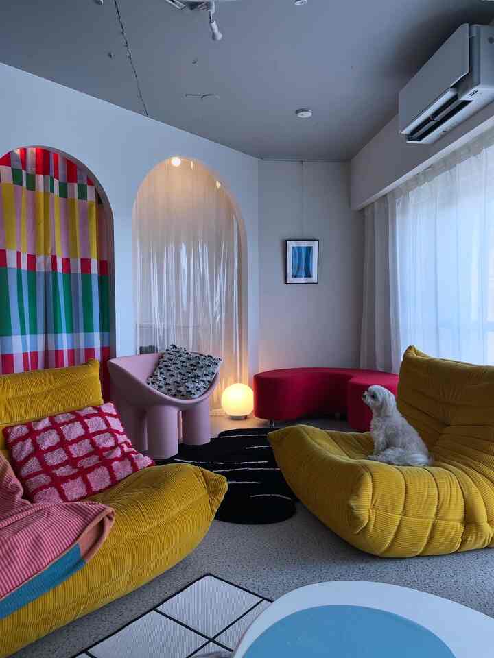 Living room with yellow sofas and red chair, white dog sitting on sofa, colorful and cozy atmosphere