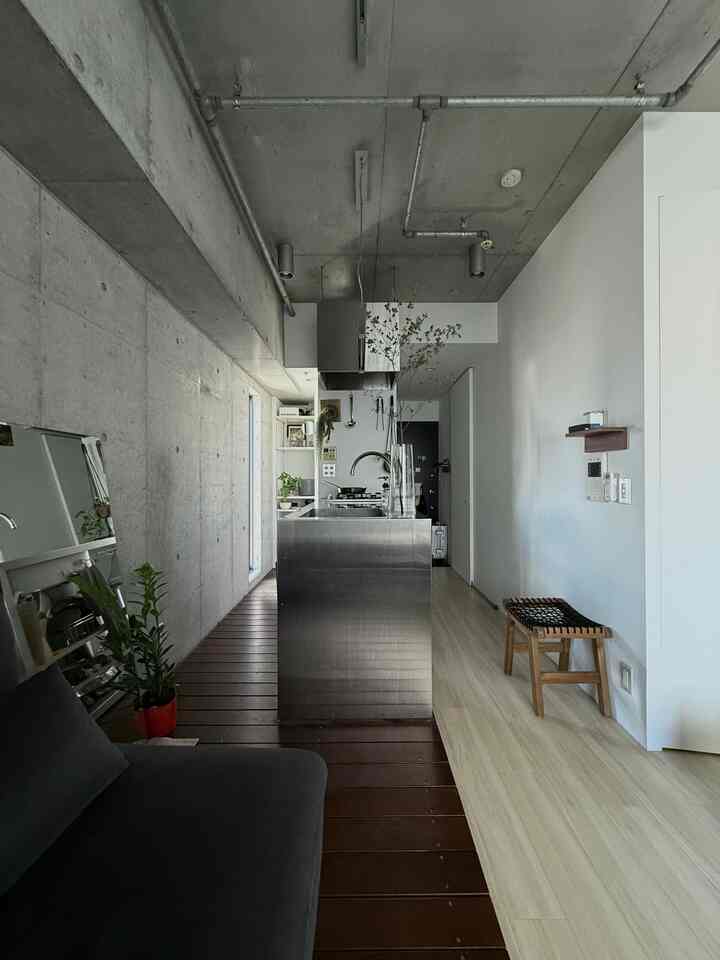 Modern single household kitchen space featuring exposed concrete wall and stainless steel kitchen island
