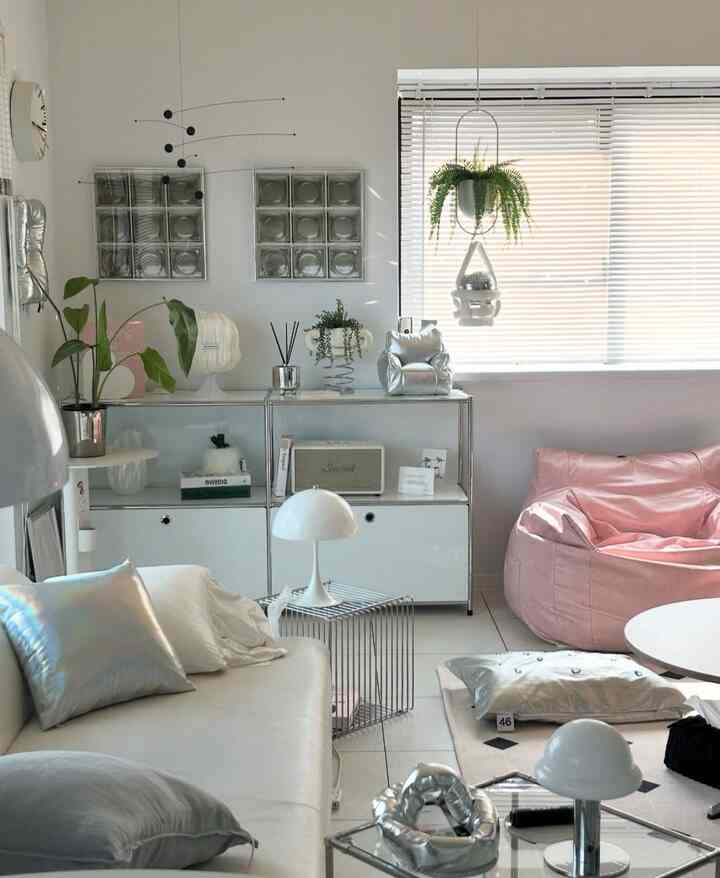 白とピンクの色調のリビング、シルバーの小物と植物が配置されたモダンで清潔感のあるインテリア