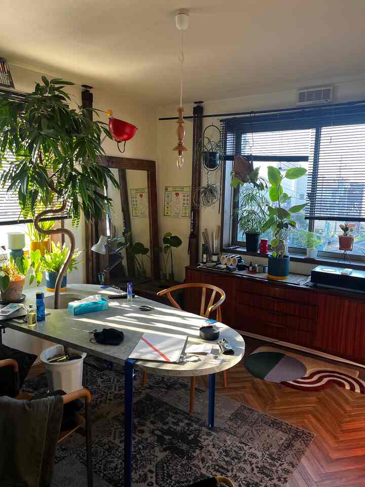 温かみのあるブラウンとホワイトのトーンのリビング、無垢材家具と植物が配置された雰囲気のあるインテリア