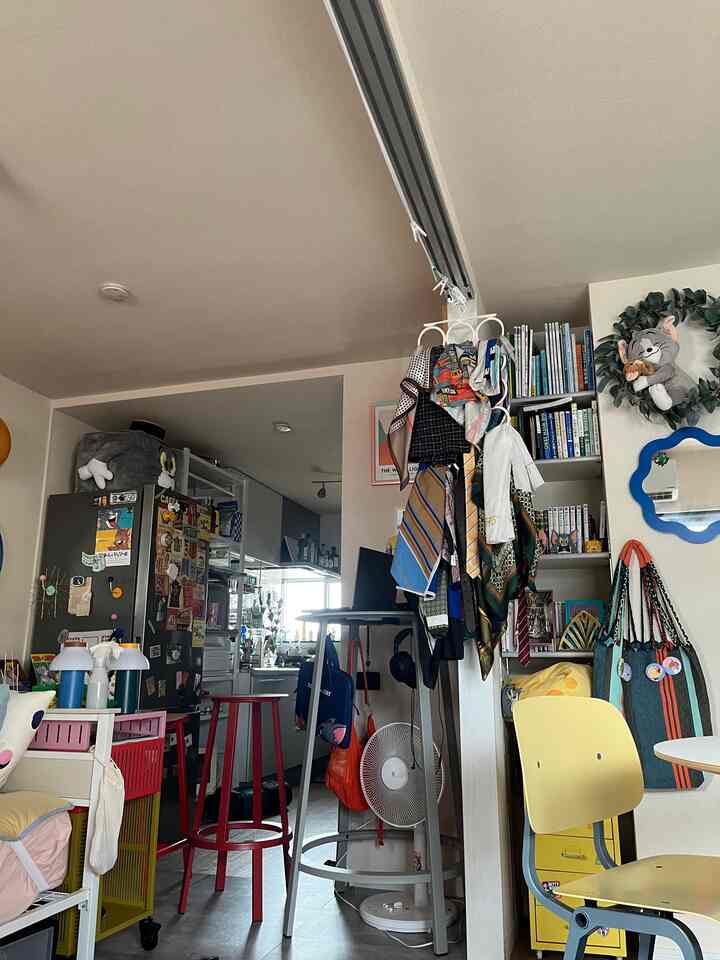 カラフルな小物とミッドセンチュリーモダンの家具が並ぶ1LDKのリビングとキッチンスペース