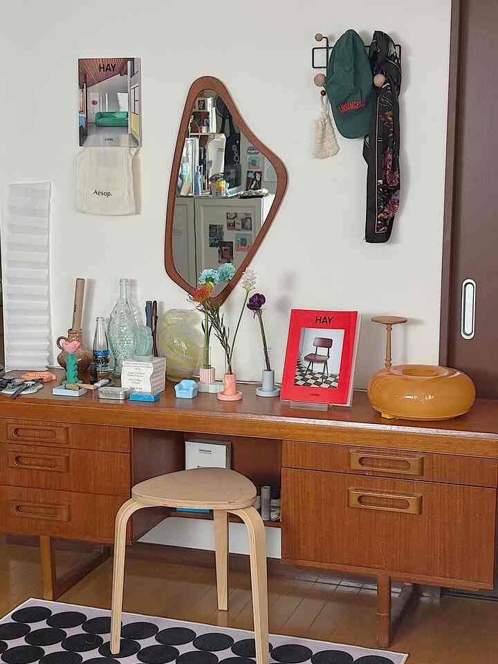 Natural wood tone vintage Nordic style desk and stool with a wall mirror and vases, creating a warm and cozy atmosphere