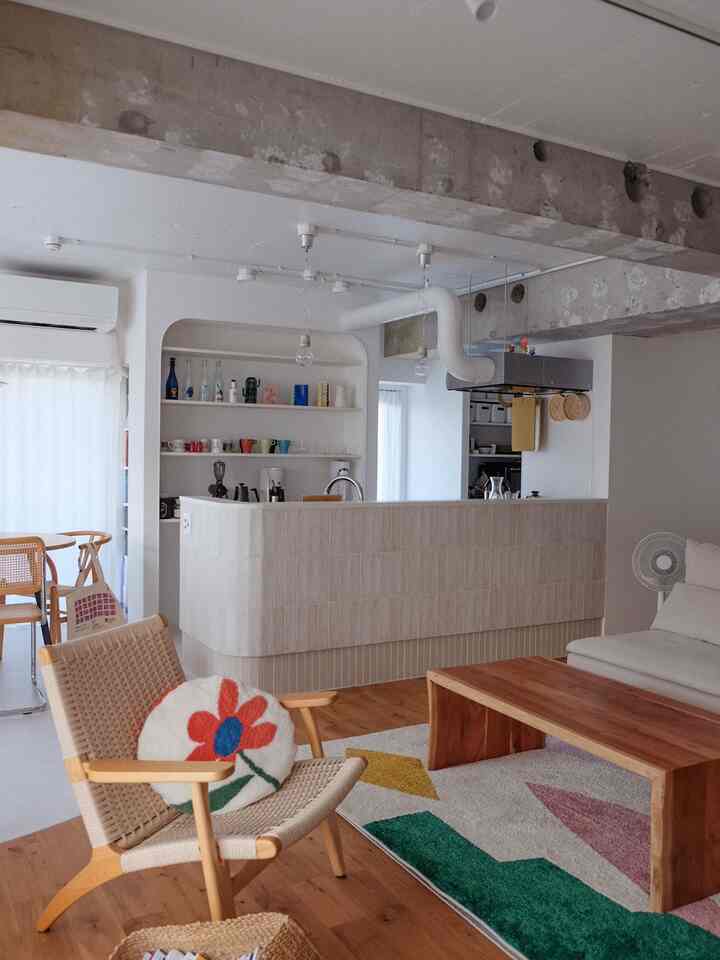 Natural tone 2LDK living and kitchen space featuring wooden furniture and exposed concrete beams in a modern setting