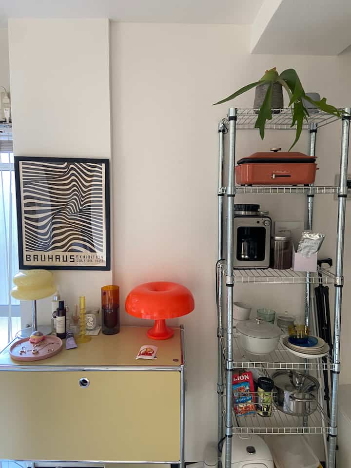 Bright yellow and red-accented mid-century modern single household space featuring metal shelves and kitchenware in a cozy setting