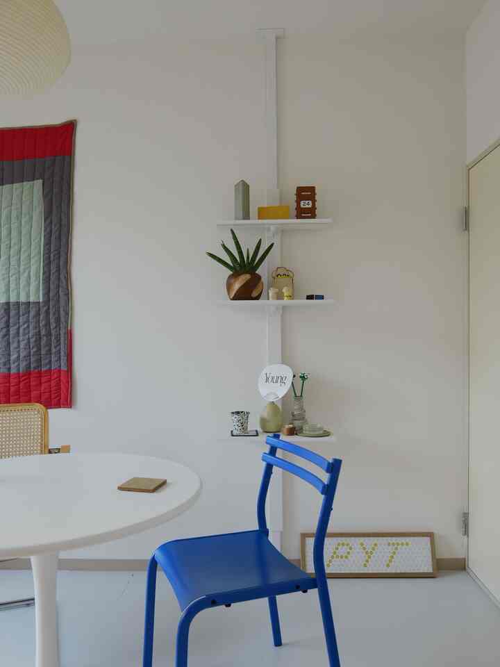 白を基調とした北欧風のダイニングルーム、青いダイニングチェアと丸テーブルが配置された清潔感のあるモダンな空間