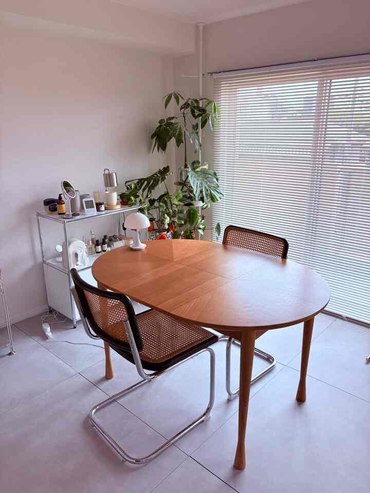 白い壁とブラウンの木製ダイニングテーブル、ラタンチェアが配置されたミッドセンチュリーモダンの印象的な空間