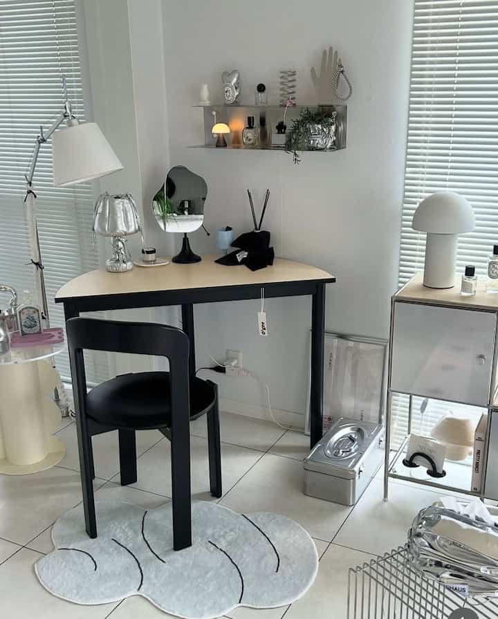 A natural modern living room corner in white and black tones, featuring a half-moon table, chair, and table lamps in a clean, minimalist setting