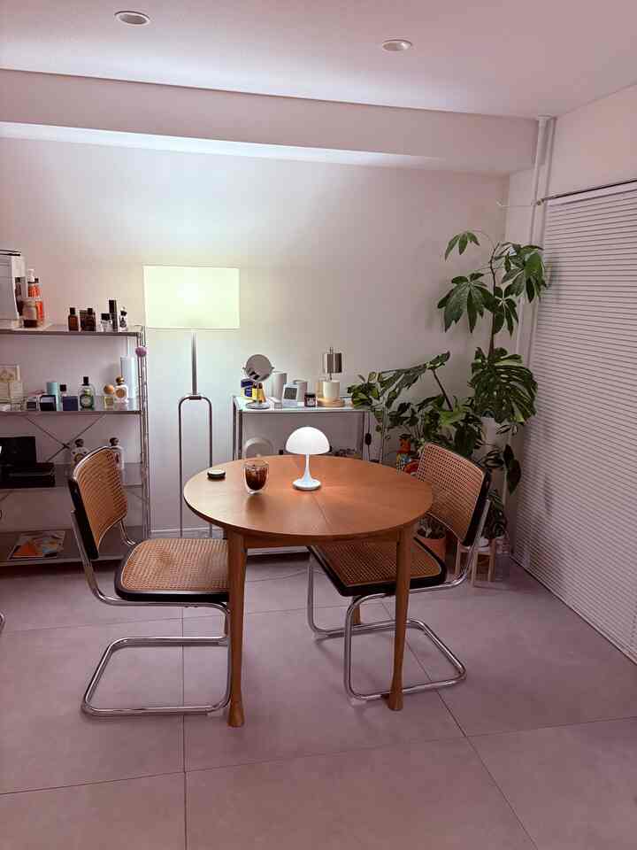 White and wood tone dining room featuring rattan chairs and round table with inorganic style ambiance