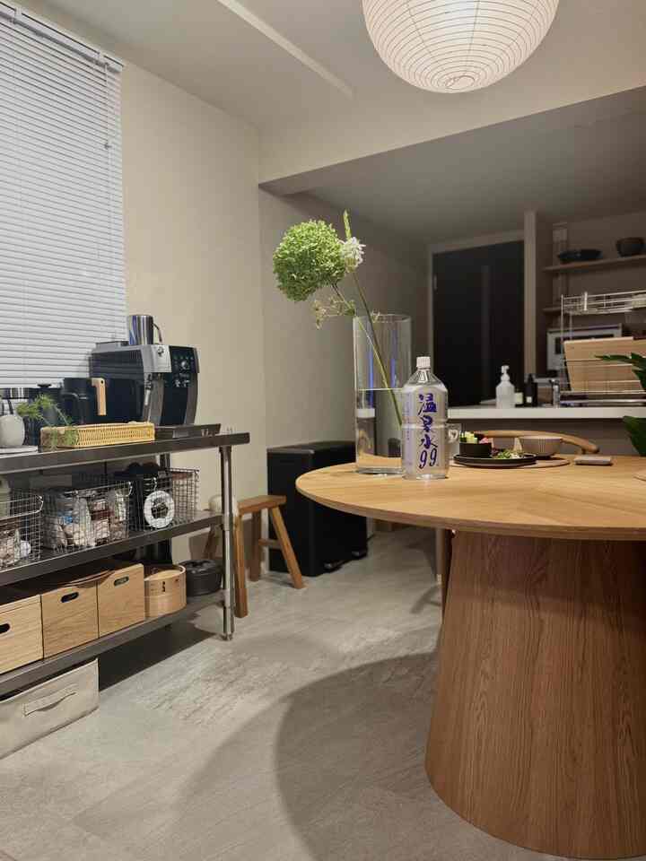 白い壁とナチュラルカラーの木製ダイニングテーブルが配置されたキッチンとダイニングスペース、シンプルで自然な雰囲気のインテリア