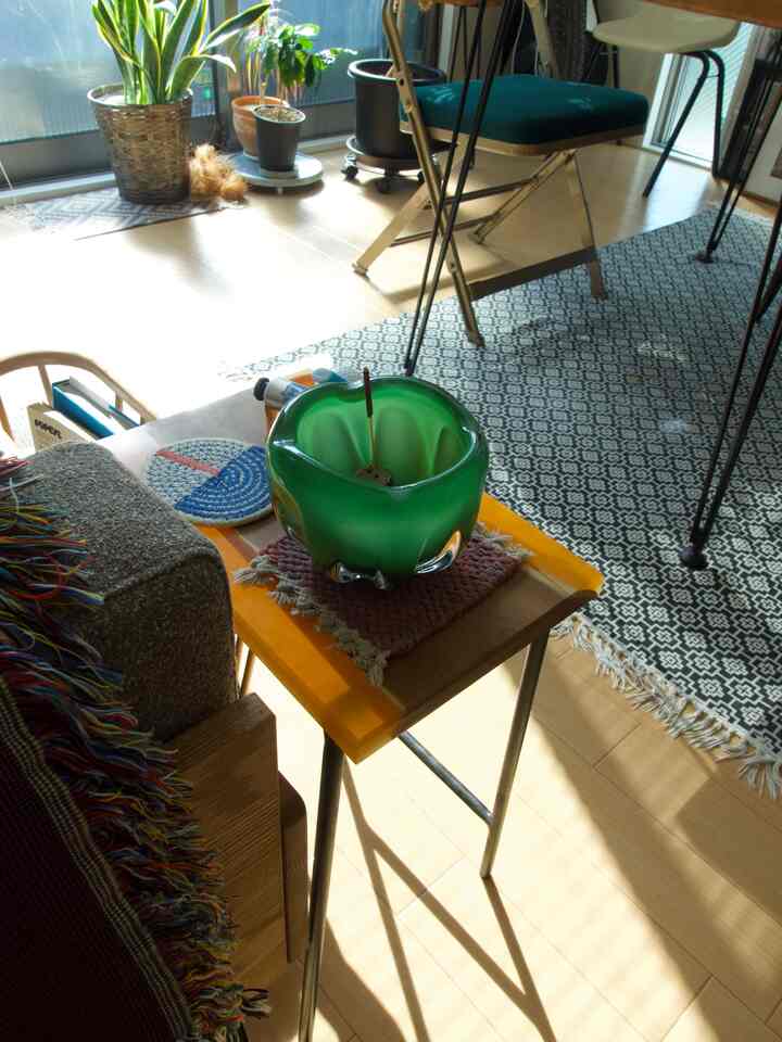 温かみのある木目調の床とサイドテーブルがあるミッドセンチュリーモダンスタイルの1LDKリビング、ダイニングチェアと植物が配置された雰囲気のあるインテリア